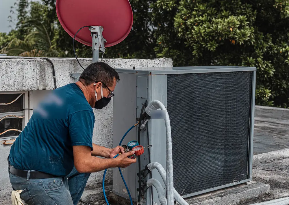 Technician checking refrigerant gauges on an air conditioner